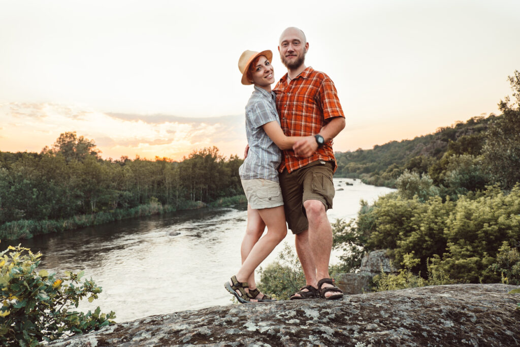 Couple looking at camera standing on top of rock. 