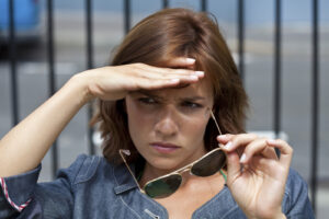 woman holding hand to light to shade her eyes 