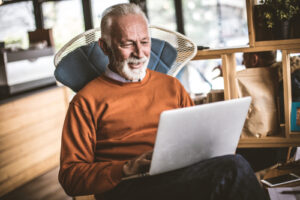 man using laptop while sitting on chair 