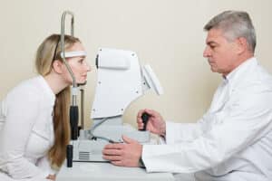eye doctor using equipment to perform an eye exam on a patient