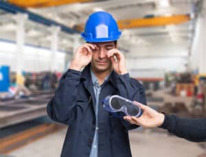 man rubbing his eyes while someone hands him protective eyewear 